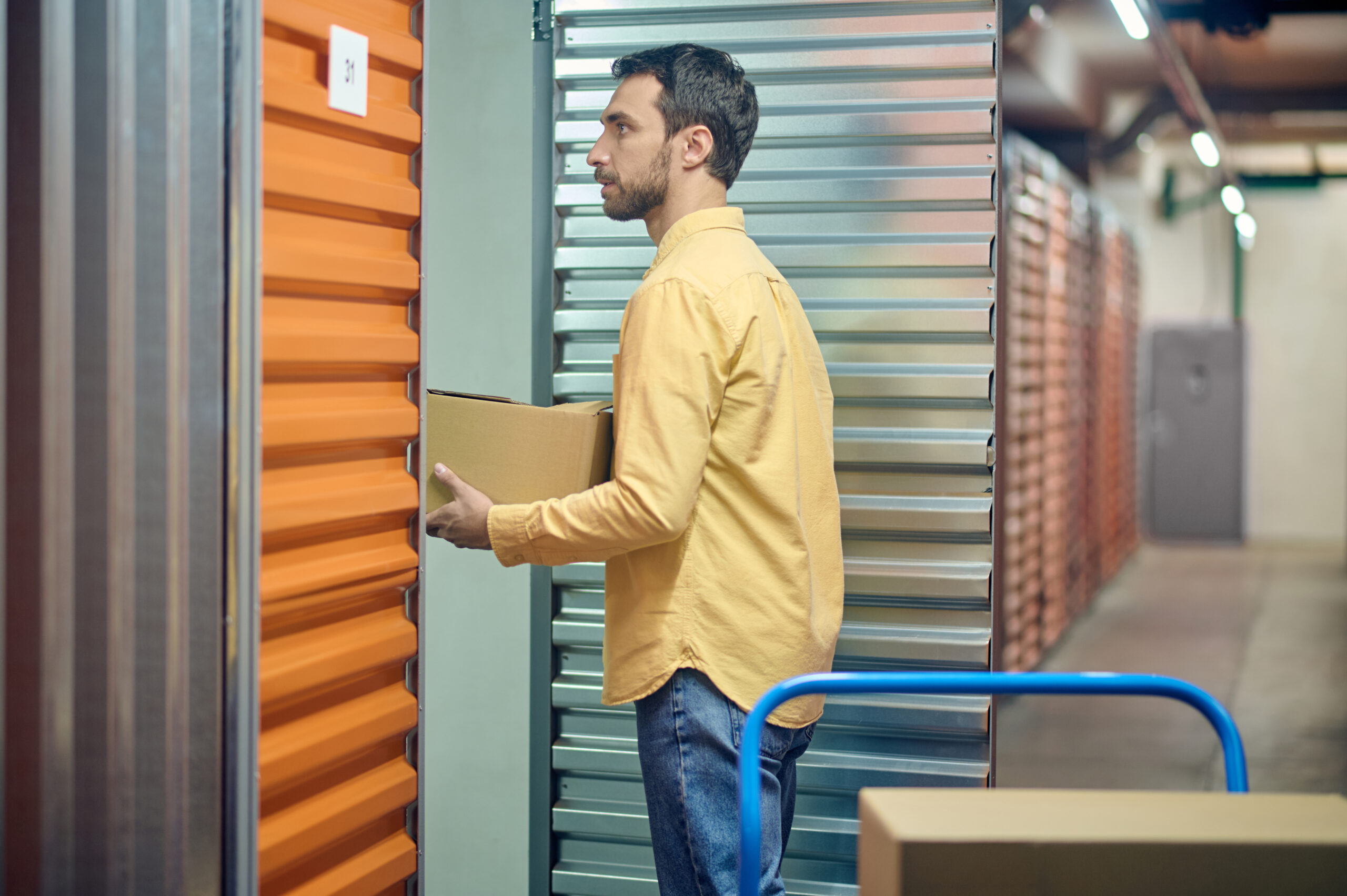 Side view of a concentrated worker with a cardboard box standing before the open shipping container